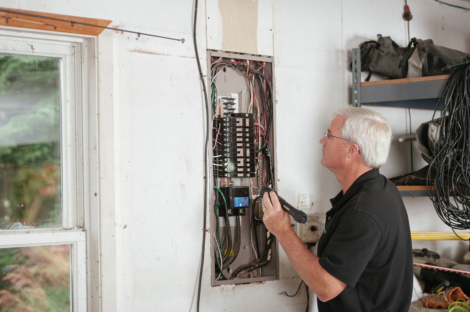 Professional residential electrician examining a home electrical panel